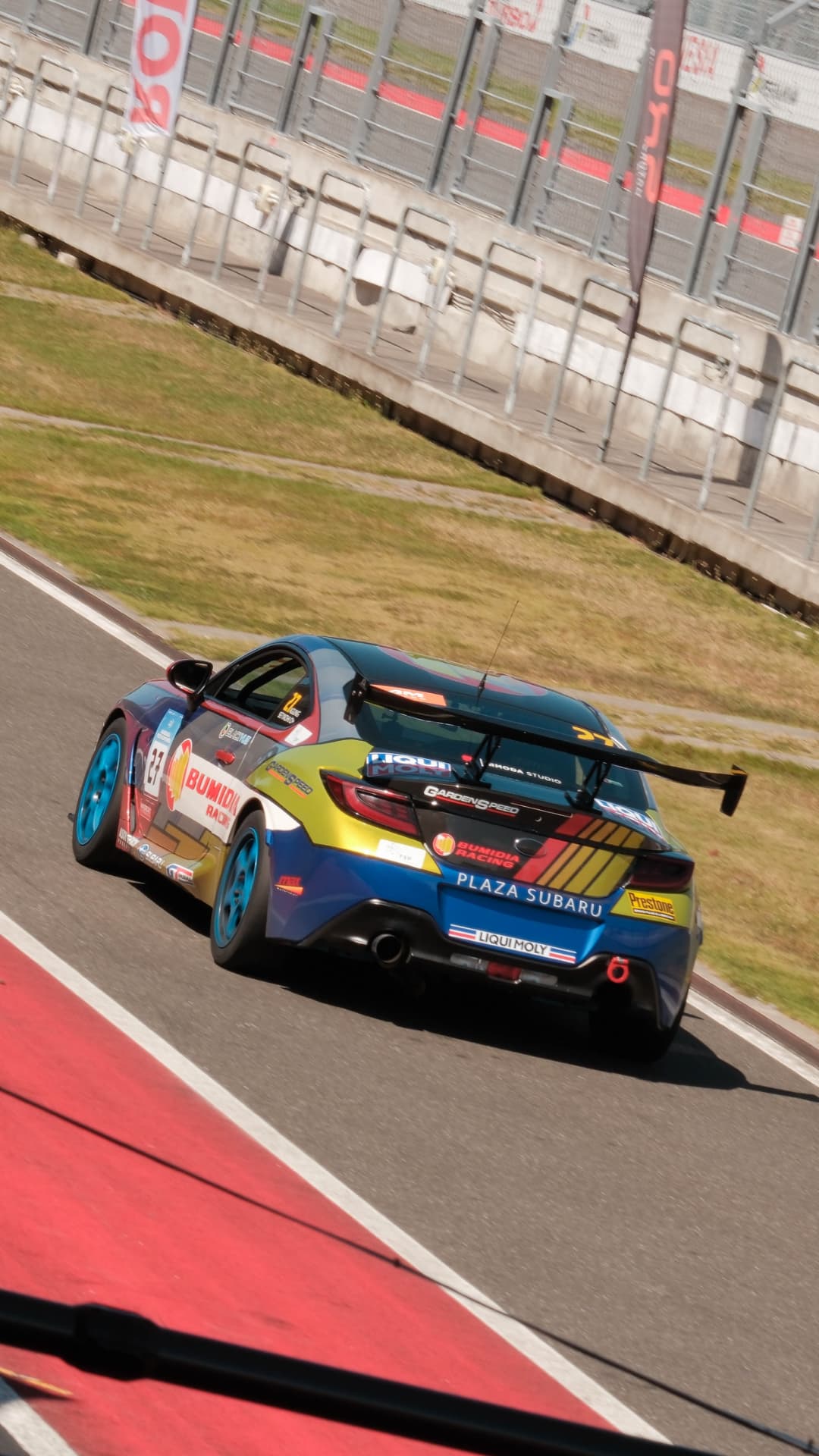 Blue and yellow Bumidia Racing BRZ rejoining the circuit