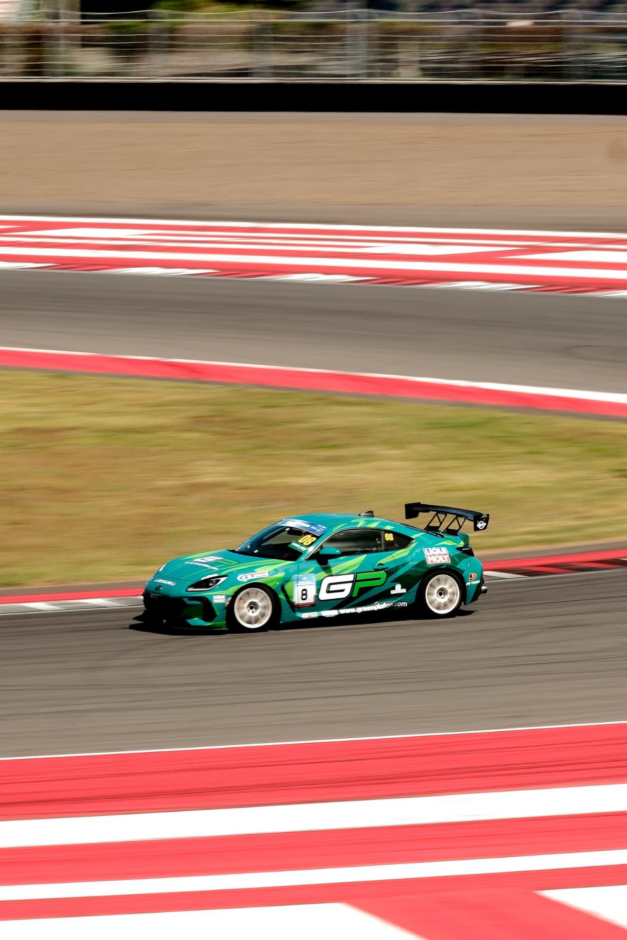 Green Greenplafon BRZ crossing the red and white kerbs